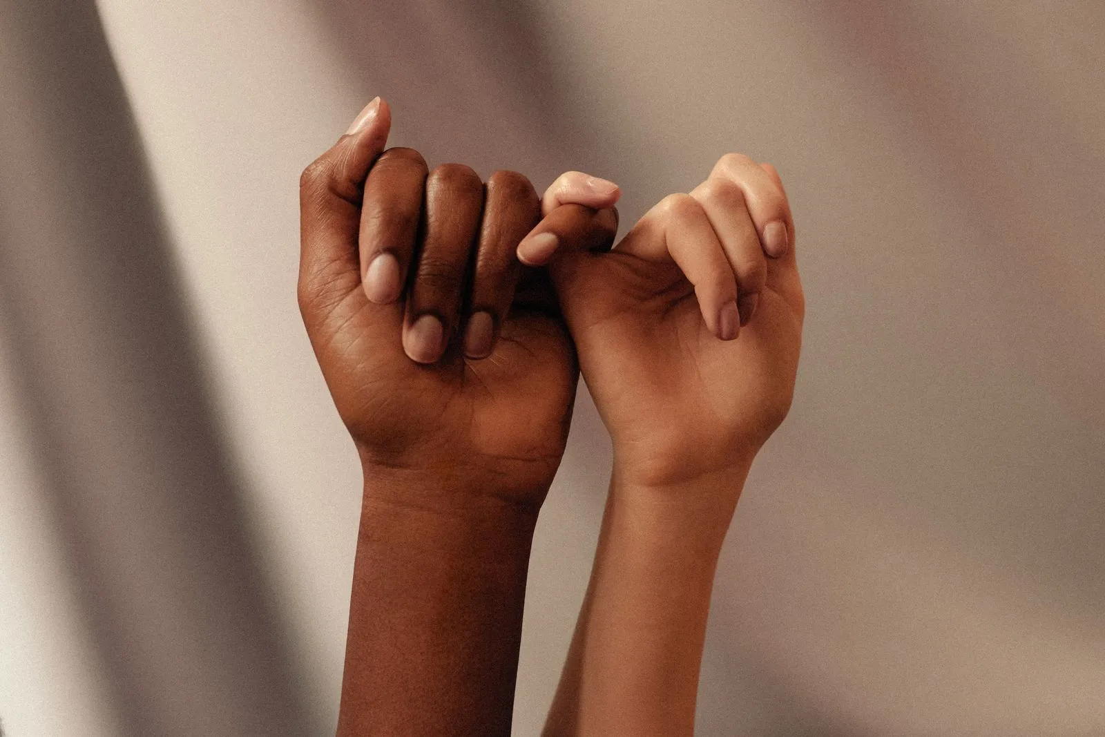 Two hands holding each other in front of a curtain.